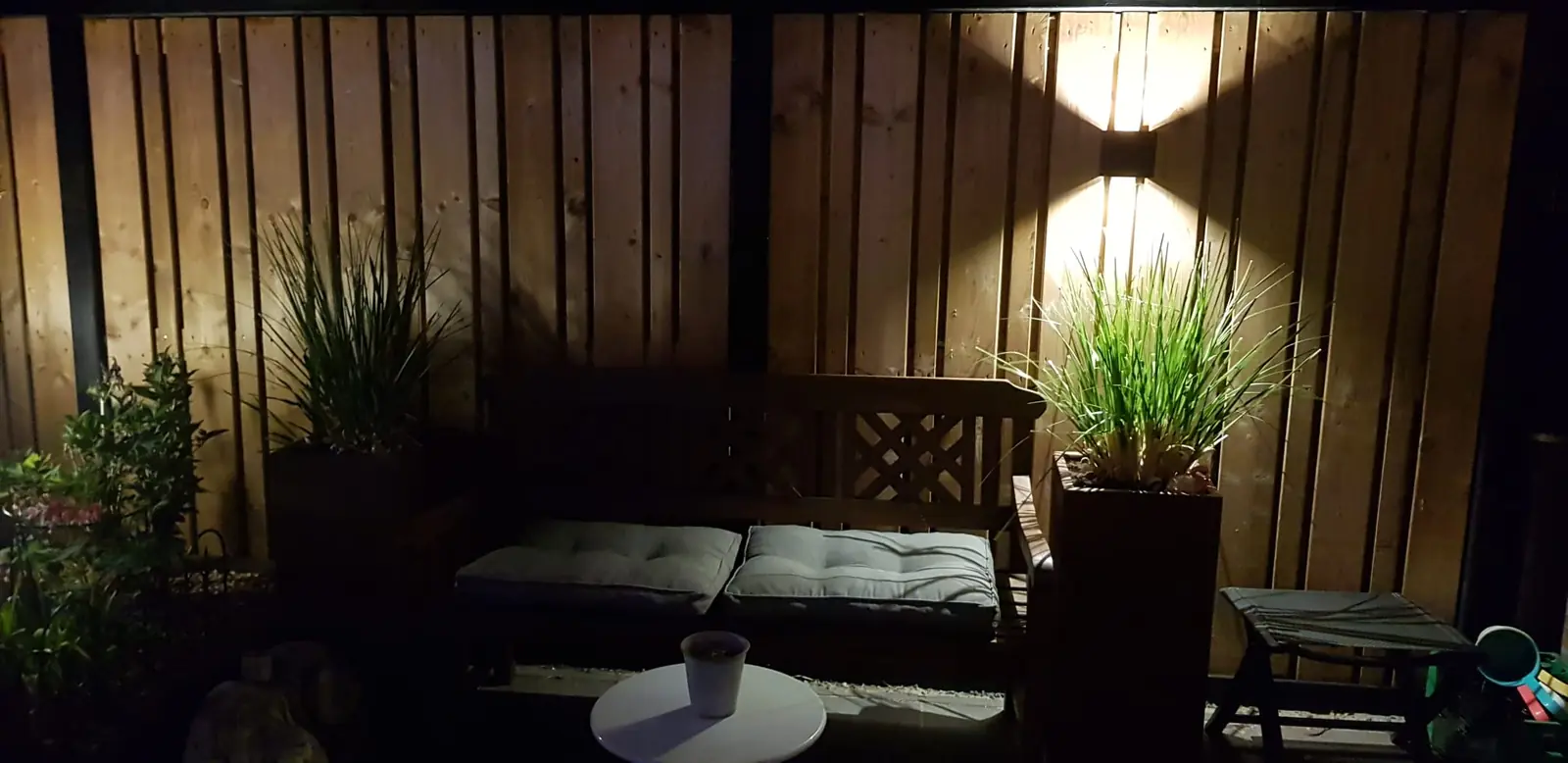 Tuinverlichting op een houten schutting en in plantenbakken